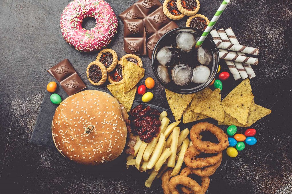 Junk food concept. Unhealthy food background. Fast food and sugar. Burger, sweets, chips, chocolate, donuts, soda.